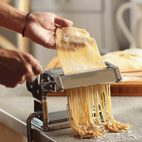 Köchin an der Nudelmaschine macht Pasta
